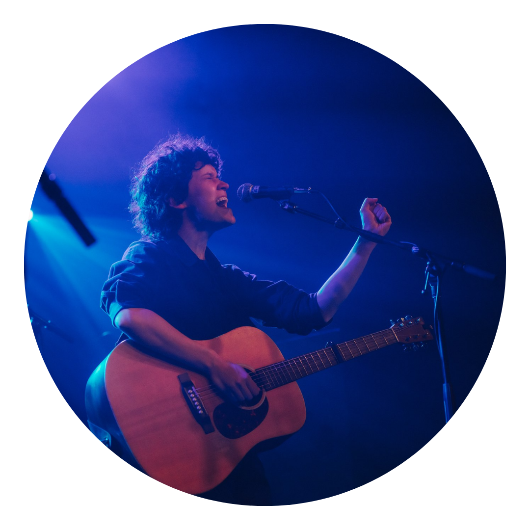 S LaJoye singing in front of mic holding a guitar